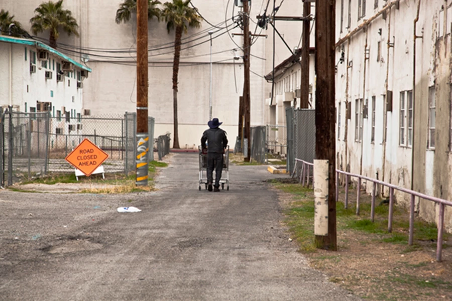 בתצלום רב עוצמה אחר נראה גבר בכובע בוקרים שחור דוחף עגלת סופרמרקט אל עבר סמטה ללא מוצא המתעלם מהשלט לפניו