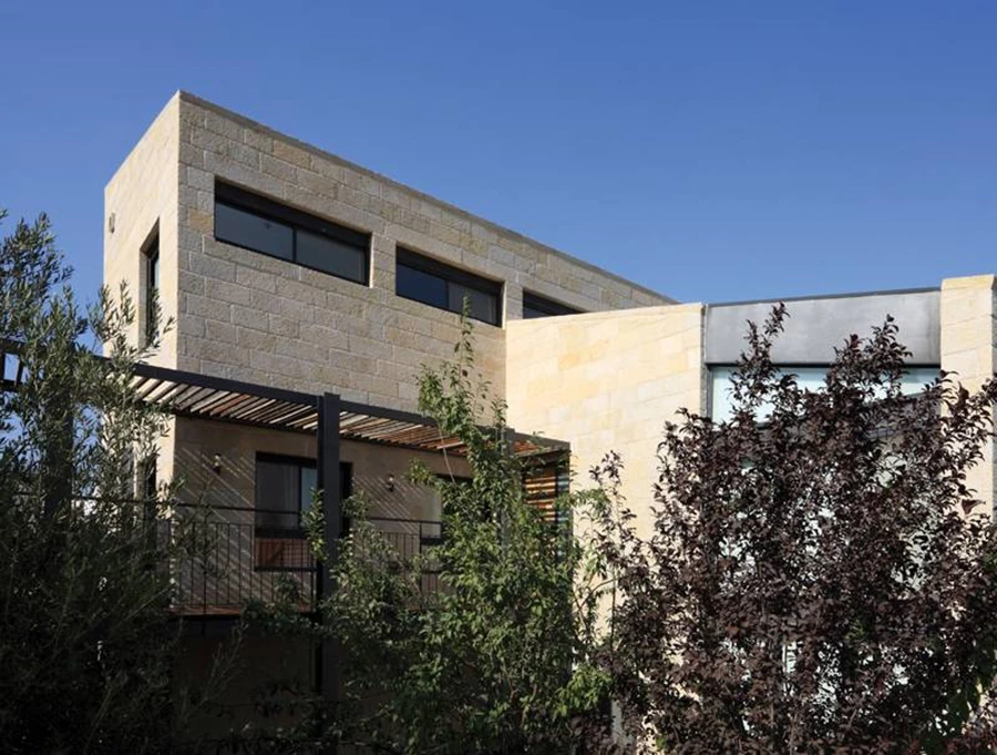 הבית במבט הרחוב - מוצנע מאחורי שורת עצים גבוהים כשרק מסת האבן והברזל מבצבצת בעדה