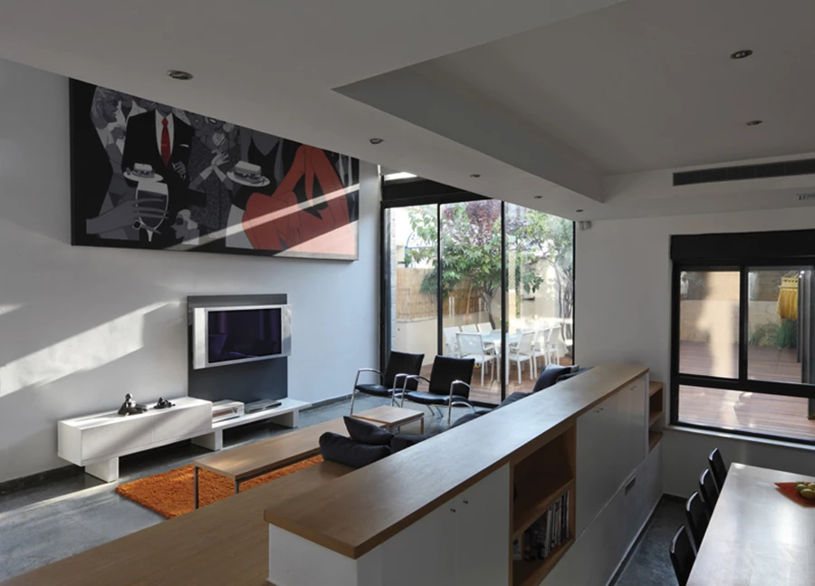 מבנה מפלסים בקומה התחתונה קושר את חללי המטבח והסלון בקשר ישיר, ויחידה בנויה משרתת את שני האזורים - במטבח היא משמשת לצרכי אחסון, ובסלון מהווה את בסיסה של מערכת ישיבה המשלבת גם משטחי הנחה נוחים.