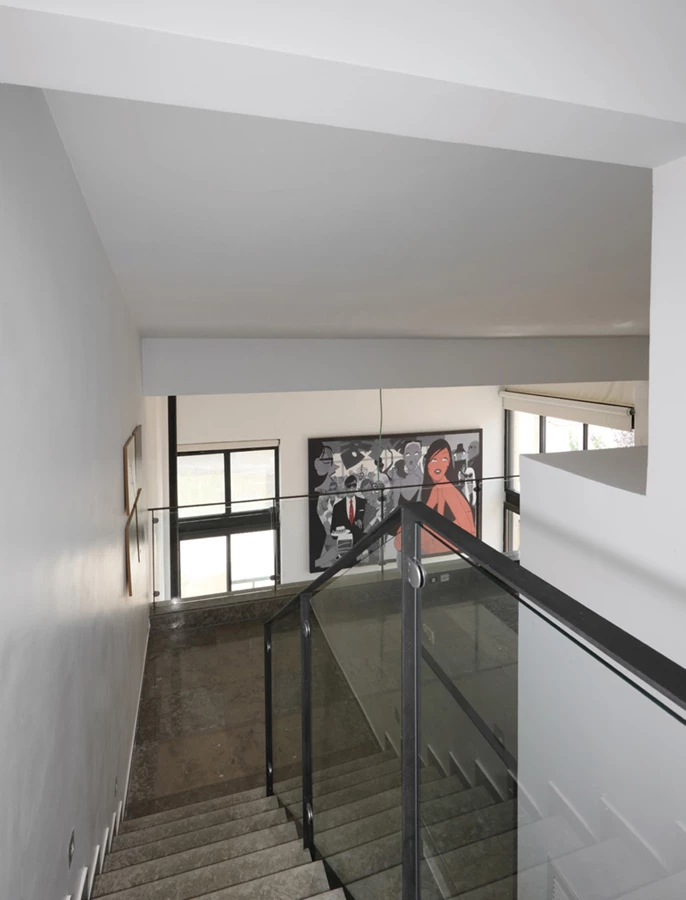 רם המדרגות המוביל אל יחידת ההורים בקומה העליונה - מעקה שקוף מקנה ממד של פתיחות וחיבור אל הקומות התחתונות, ואף מאזור זה ניתן להתבשם מנוכחותה של עבודת האמנות המעטרת את קיר הסלון.