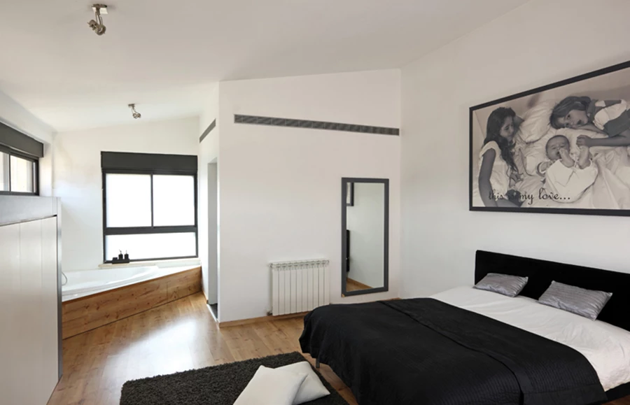 יחידת ההורים שבקומה העליונה - חלל משופע תקרה )כמתחייב בתב”ע של היישוב( הנפרש כ”אופן ספייס” מרוצף עץ, ומשלב בשטחו אמבט פתוח וריהוט בנוי המשתלב לאורך פתחים עליונים ומשמר חזות נקייה ואוורירית. ה”בונוס” של החדר: מרפסת קטנה ממנה ניתן להשקיף אל נוף הכביש העולה לירושלים.