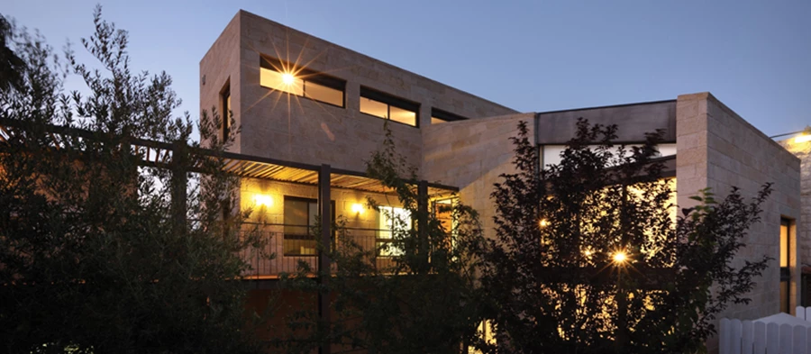 הבית, הגשר והחצר בשעות החשיכה, כשתאורה מוקפדת מאצילה ממד קסום.