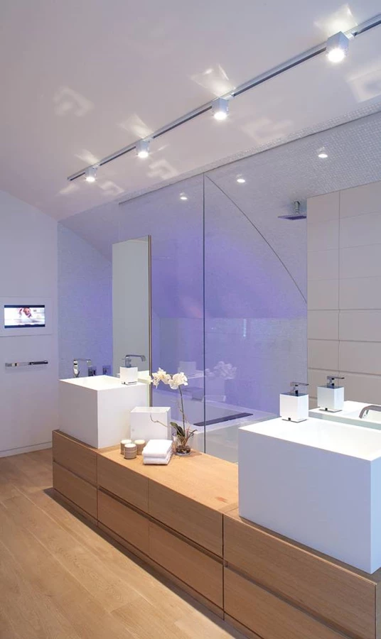 בתמונות: חדר הרחצה של יחידת ההורים: שידה אורכית נמוכה שבשני קצות משטחה העליון ניצבים כיורים מעוצבים כעין תיבות רבועות וברזים צדדיים ש