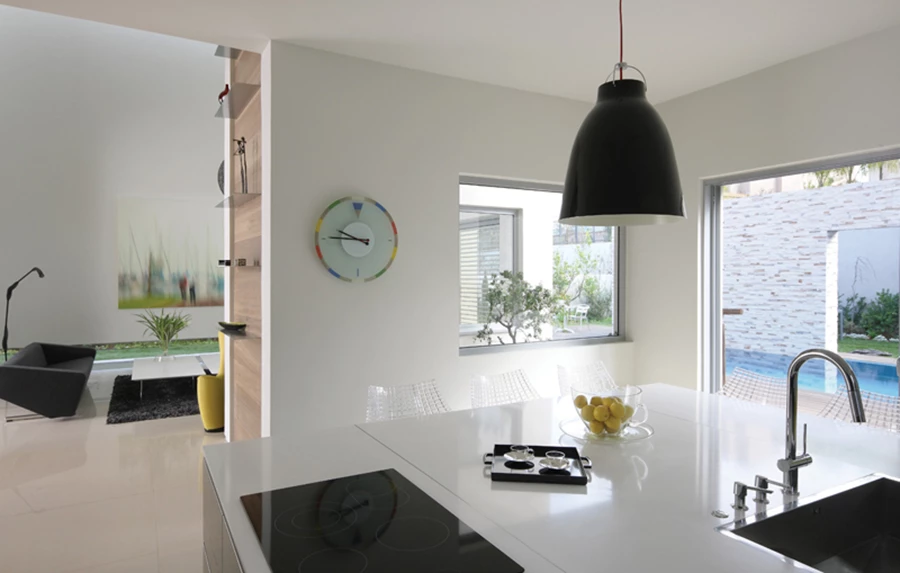 בהיקף החלל: יחידת קיר גדולה המשלבת בתוכה את המקרר ותנורים, ומערך סלוני בחזותו המשלב שתי יחידות ארוכות בהפרש גבהים קל זו מזו ויחידה תלויה מעל הנמוכה שבהן, שמשטחה העליון מחופה זכוכית צהובה. היחידות בגימור שלייף לק בגווני שחור ואפור, משטחי אבן קיסר לבנה ושחורה, גוף תאורה בסגנון תאורת במה וכיסאות בר גבוהים עשויים פלסטיק במרקם משבצות. גוף תאורה: “יאיר דורם”.