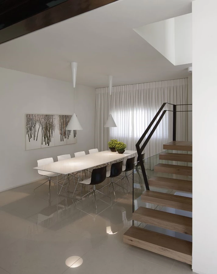 מבט מאזור הסלון - פיר המעלית הקושר את הקומות וגרם המדרגות הנתמך עליו, ופינת האוכל הממוקמת בקדמת המרחב כאזור נוח לאירוח, אינטימי ומוגדר.