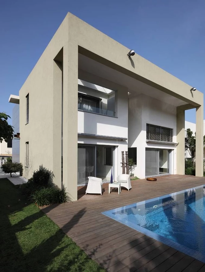 החזית האחורית - מתאר הקוביות “עטוף” במבנה שער מחופה טיח שאף מקרה את דק העץ ביציאה מהבית. הדק סובב בריכת שחייה שתוכננה עם שפת גלישה, בשטחו מוצבות פינות ישיבה מסוגננות והוא תחום במדשאה.