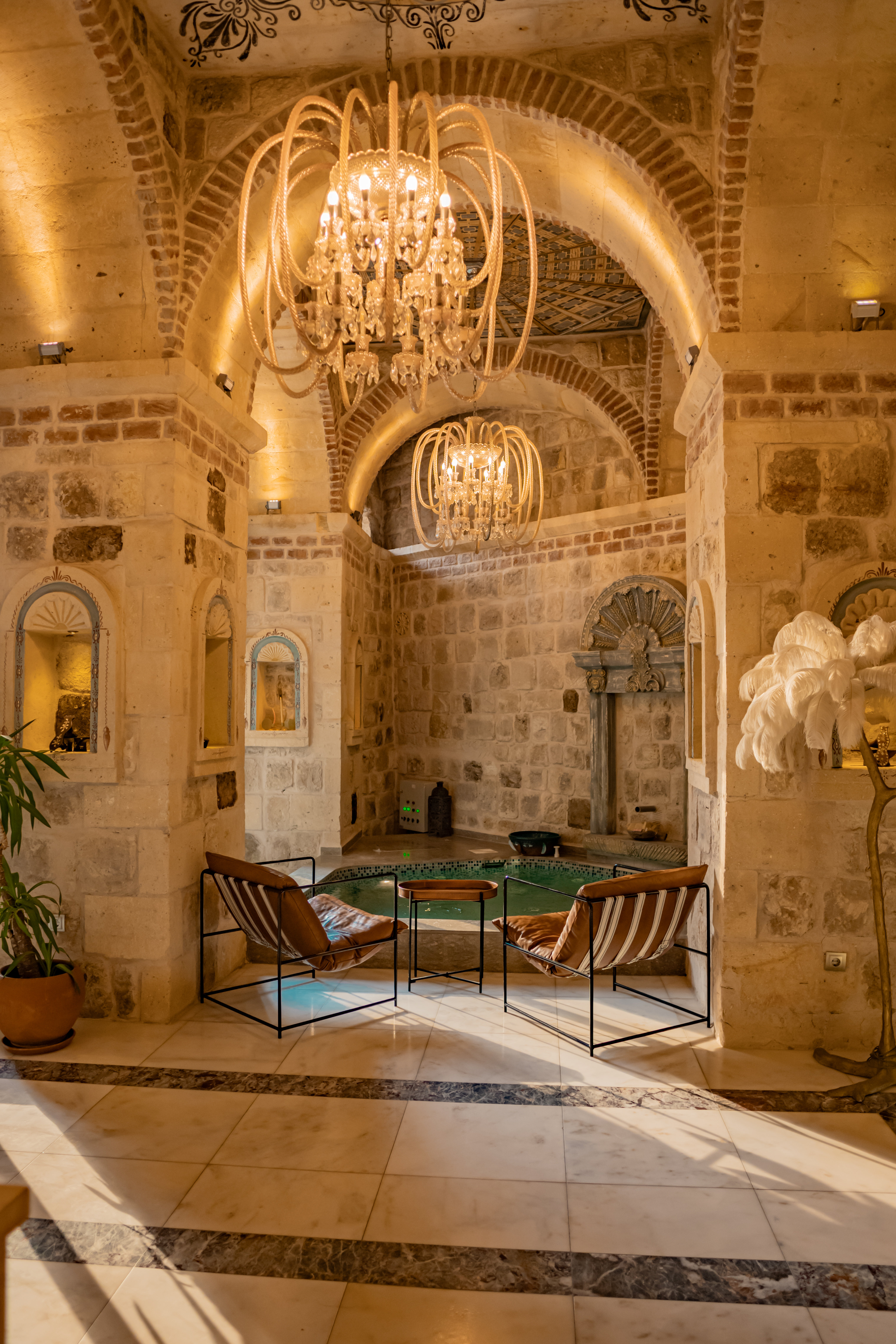 הכניסה לספא של Elika Cave Suites Cappadocia, עם פינת ישיבה מול קיר אבן ובריכה פנימית. © 2026 Hilton