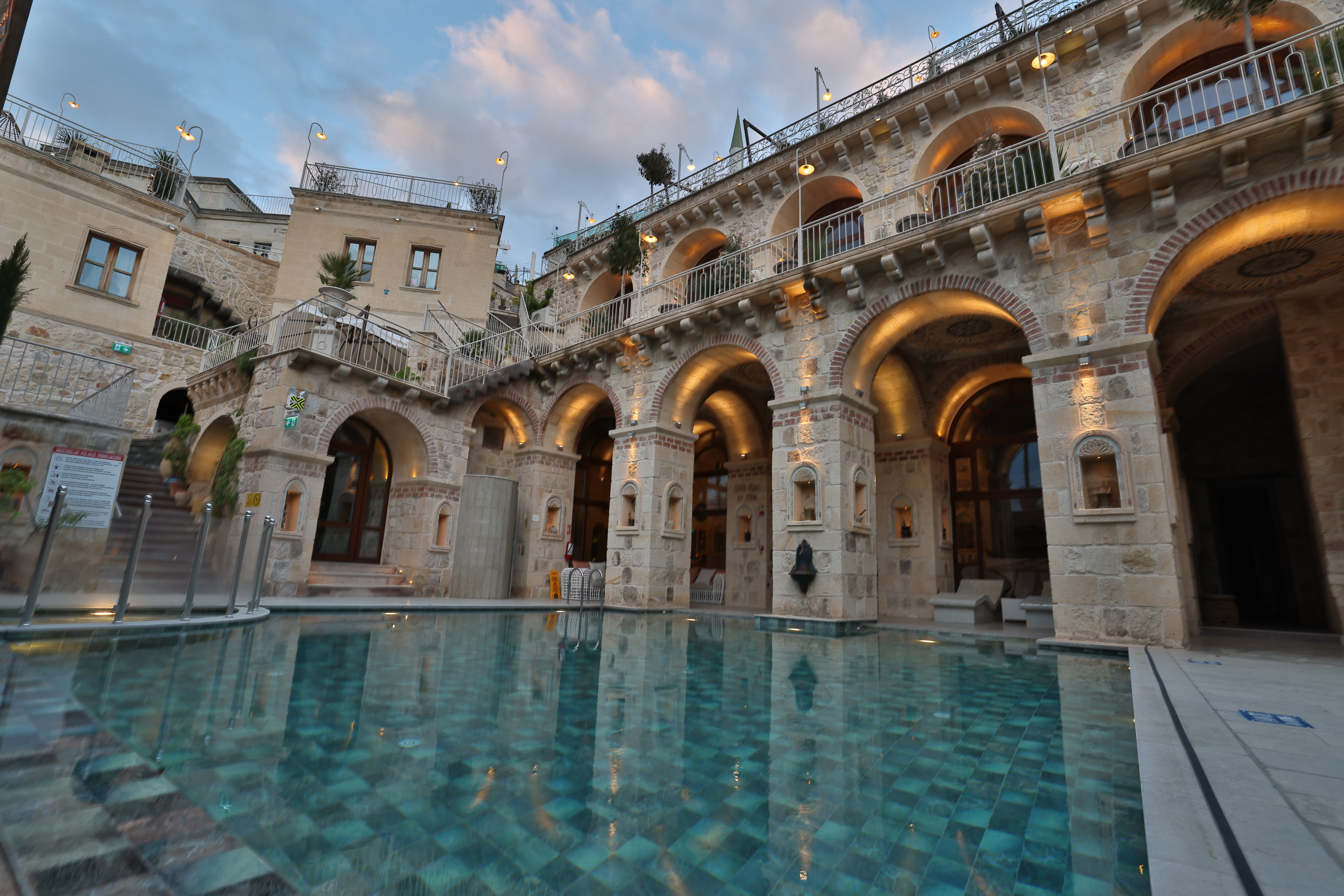הבריכה החיצונית של Elika Cave Suites Cappadocia, מוקפת מבני אבן עם פתחים מקושתים. © 2026 Hilton
