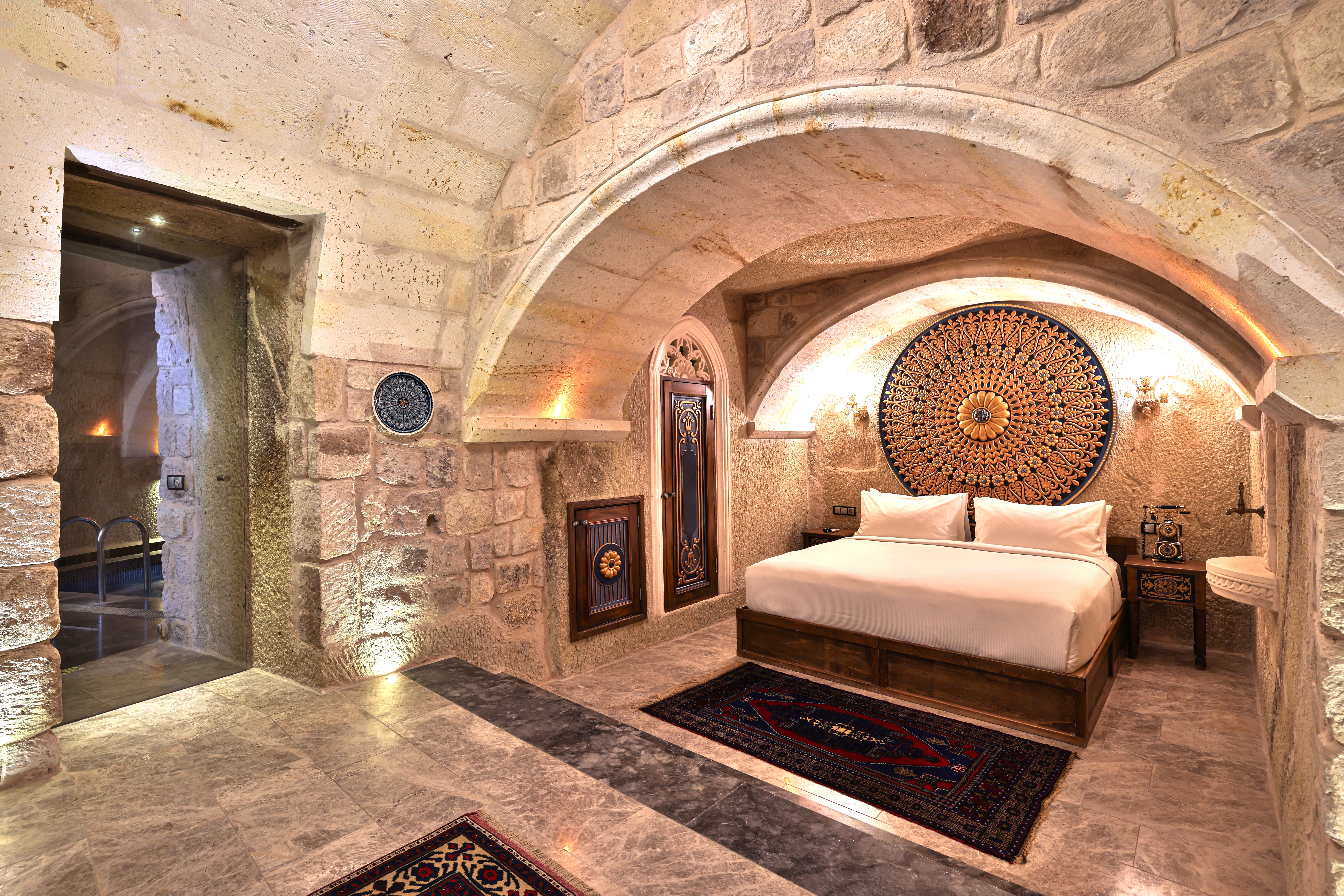 סוויטת King Cave Junior עם בריכת טבילה ב־Elika Cave Suites Cappadocia, עם תקרת אבן מקושתת ופתח שמוביל אל אזור הבריכה. © 2026 Hilton